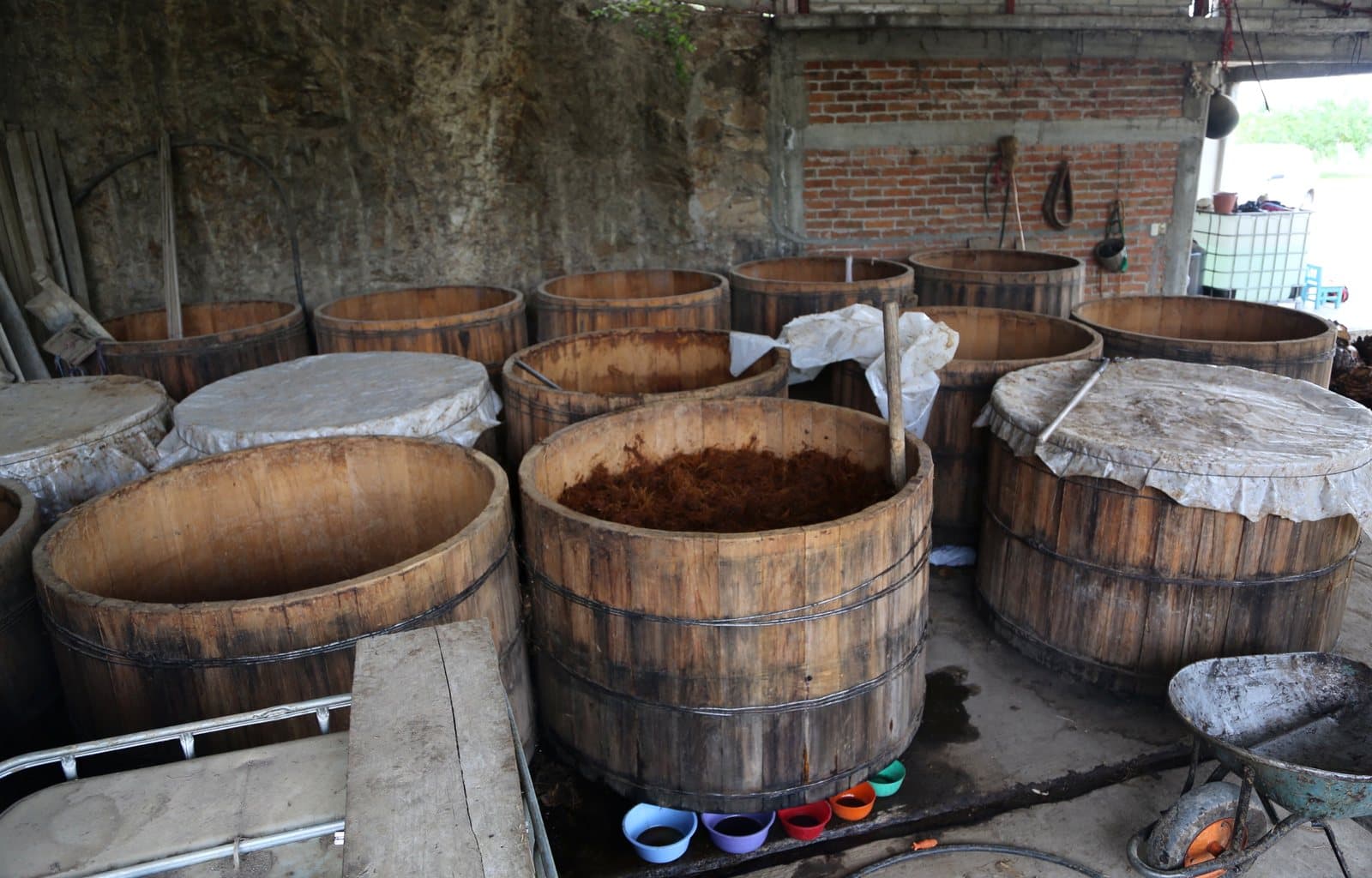 Open wooden fermentation vats, one filled with agave fiber