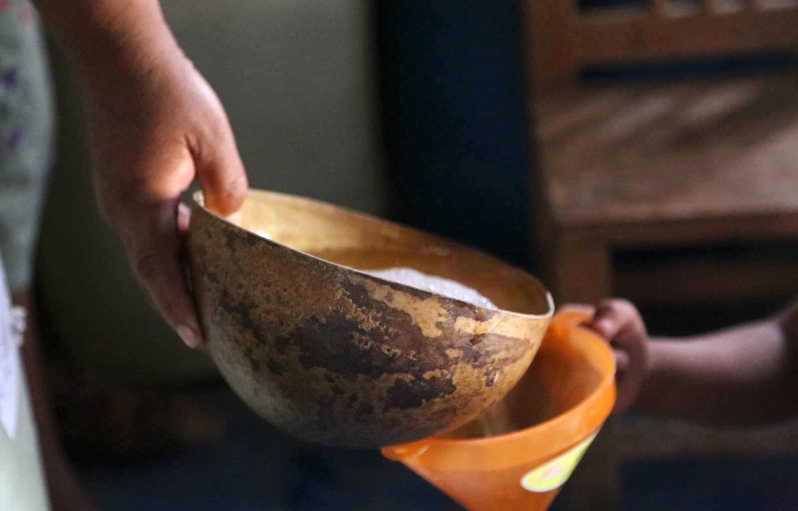 Mezcal poured from a gourd bowl, showing its bubbles