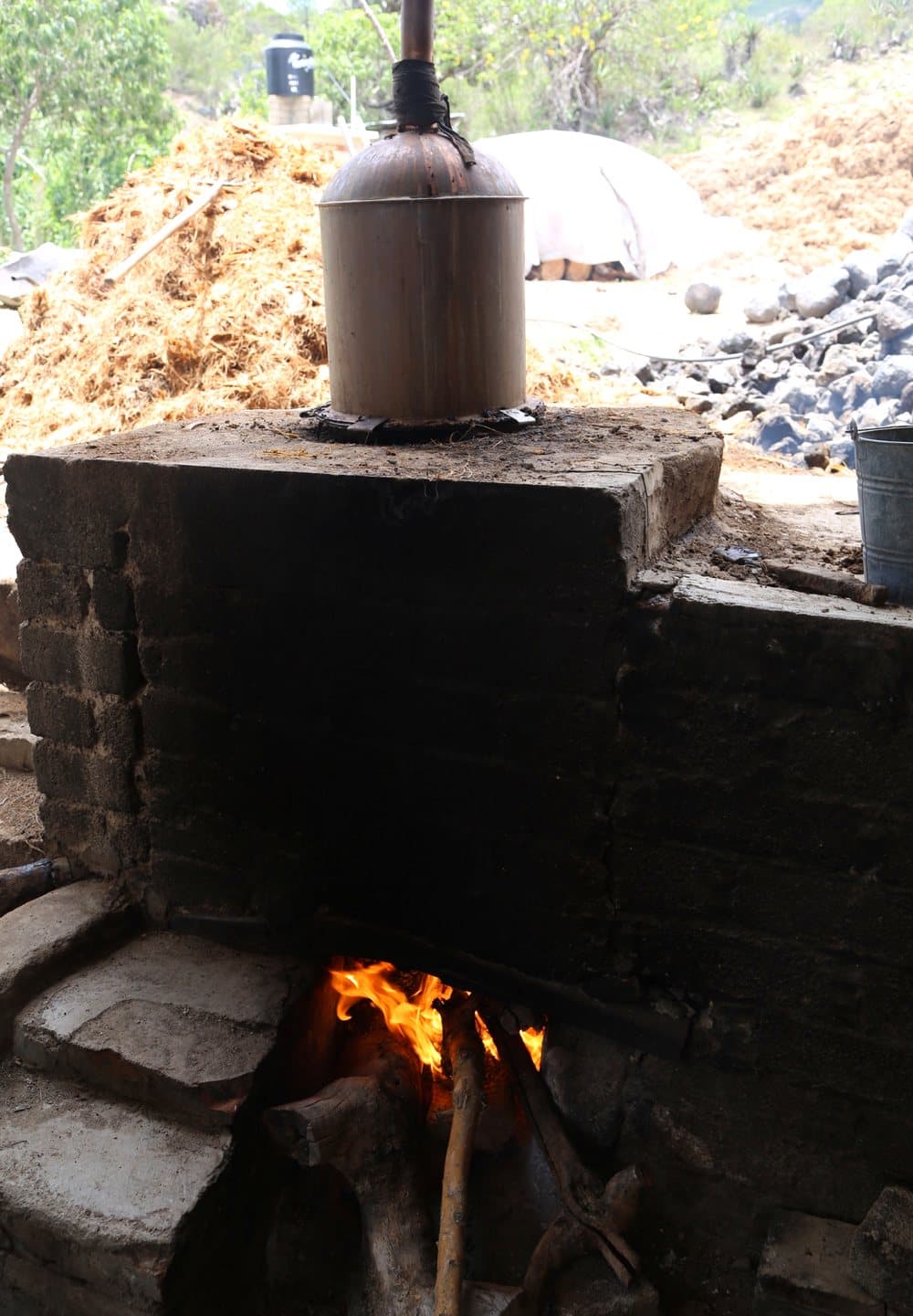 A copper still cap above a wood fire